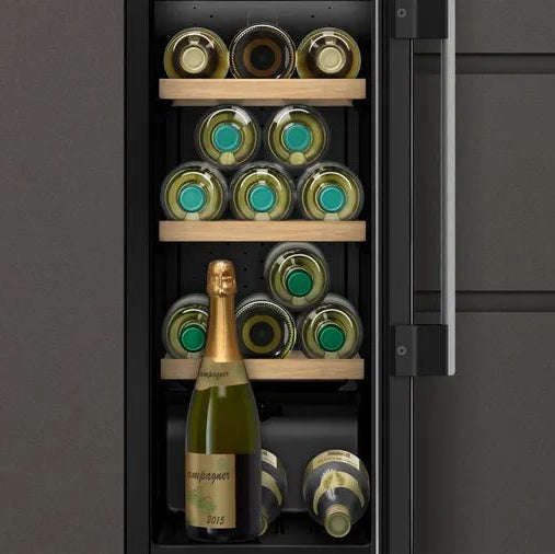 Neff KU9202HF0G fitted between kitchen cabinets, showing wine bottles on wooden shelves behind the glass door.